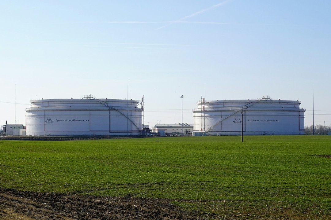 Oil storage tanks behind a green field at the Bučany petroleum storage facility in Slovakia; illustrative file photograph.